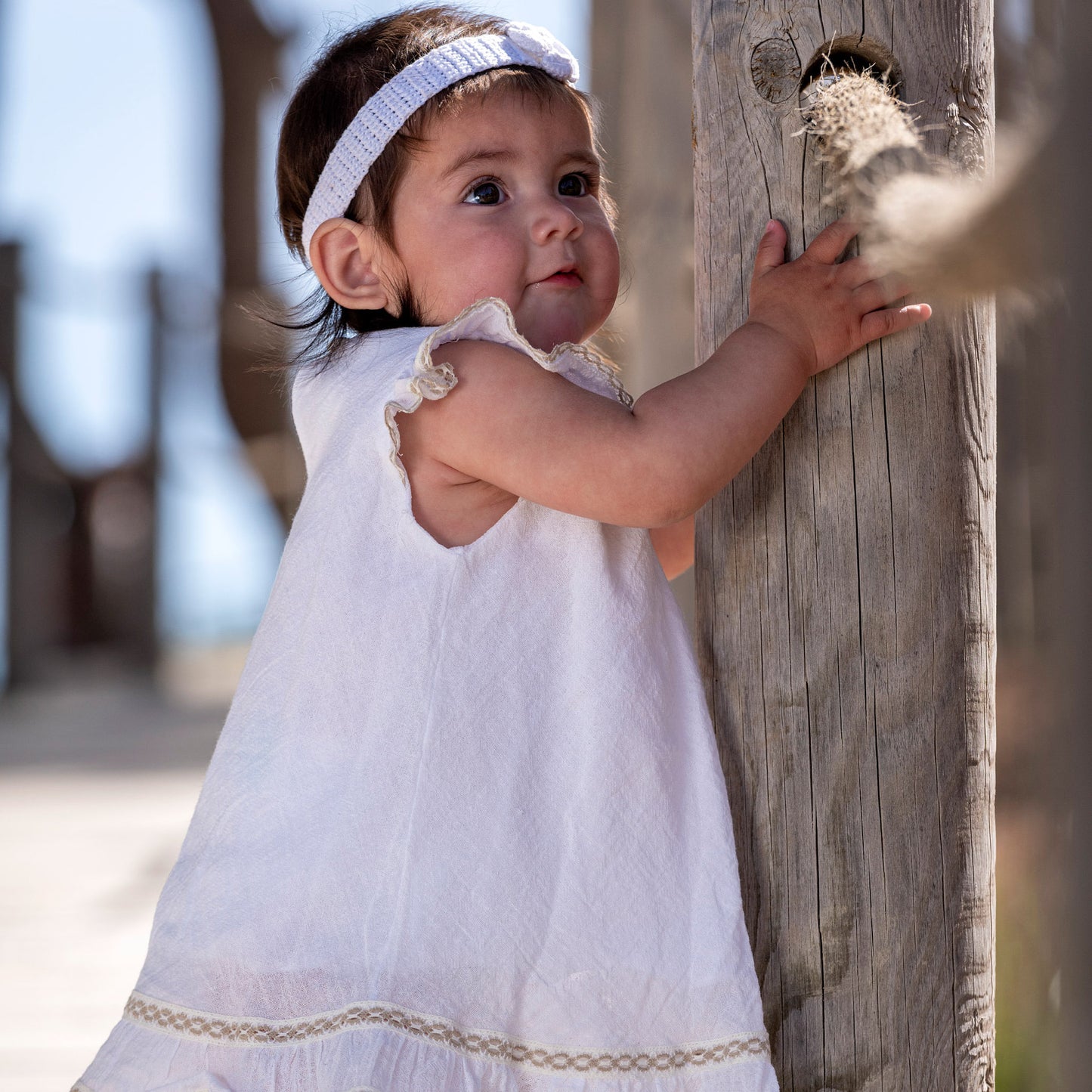 Vista lateral del vestido blanco de esilo ibicenco para bebés y niñas decorado con puntillas de algodón