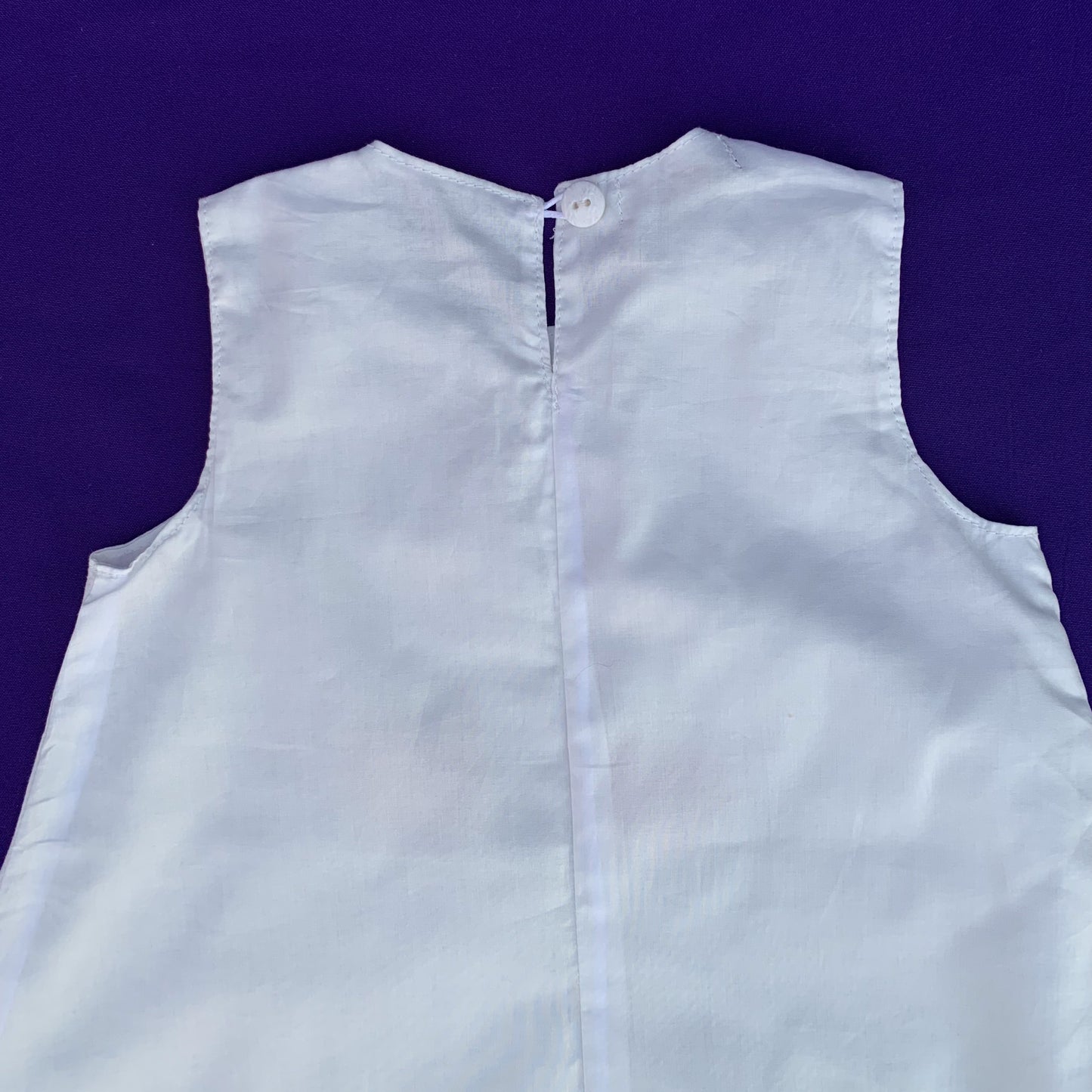 Imagen de la parte trasera del vestido blanco de algodón con flamencos pintados a mano en la que se aprecia el cierre superior con botón