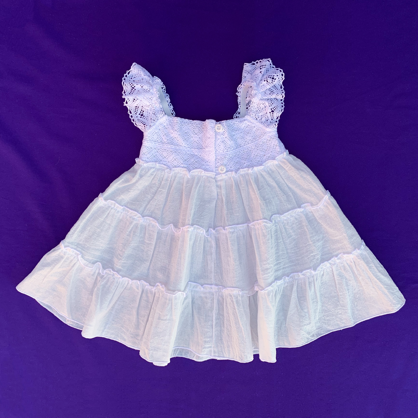 Parte trasera del vestido blanco de puntillas para bebés y niñas. Cierre de botones.