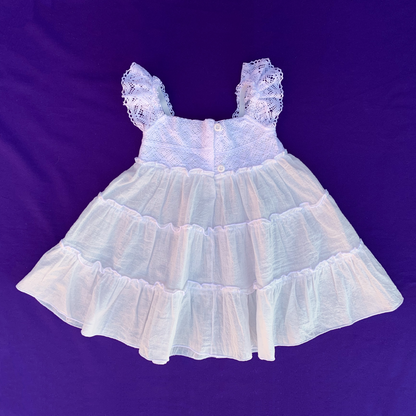 Parte trasera del vestido blanco de puntillas para bebés y niñas. Cierre de botones.