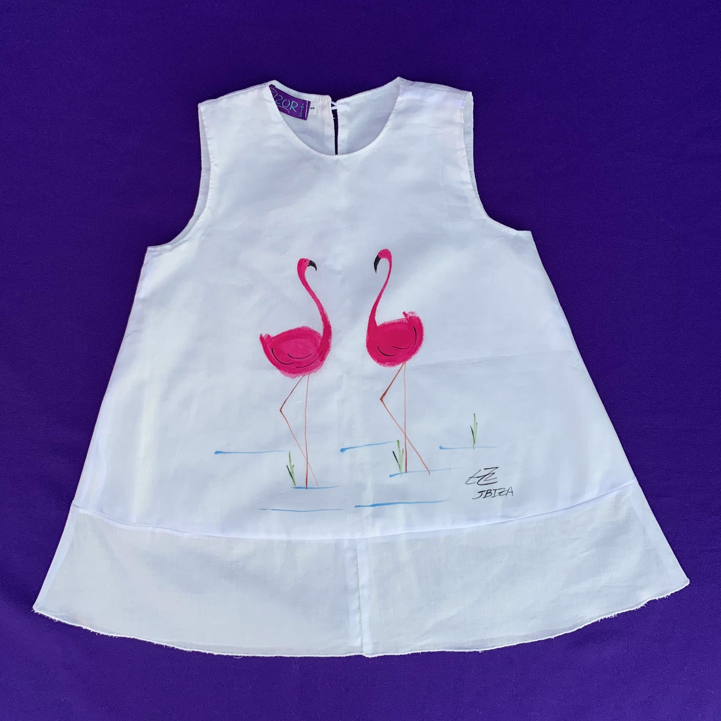 Primer plano del vestido blanco con los flamencos pintados a mano. Disponible para pedidos online a través de la tienda de Tizor Ibiza
